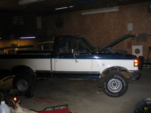 1989 Ford F-150 - This 1989 Ford F-150 pickup truck is shown in a garage with its hood raised, indicating potential mechanical work.