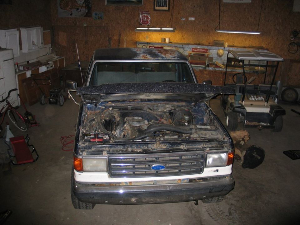 Ford F-150 truck with hood open, showing engine bay. White lower grille and bumper