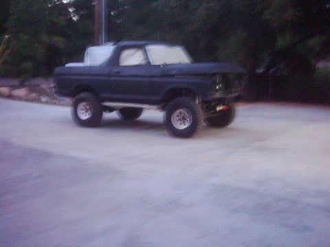 1978 Ford Bronco - This dark blue 1978 Ford Bronco is seen from a 3/4 front angle, with a white cover obscuring the roof.