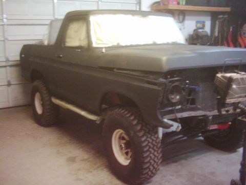 1978 Ford Bronco - A 1978 Ford Bronco is shown in a garage, undergoing repairs with its front end partially dismantled.