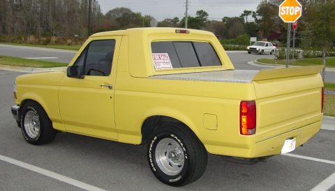 1994 Ford Bronco - Yellow 1994 Ford Bronco parked on a street with a "For Sale" sign visible.