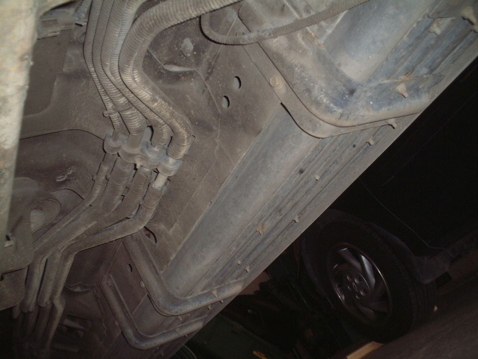 Underside of vehicle showing routed fuel and brake lines along the frame rail