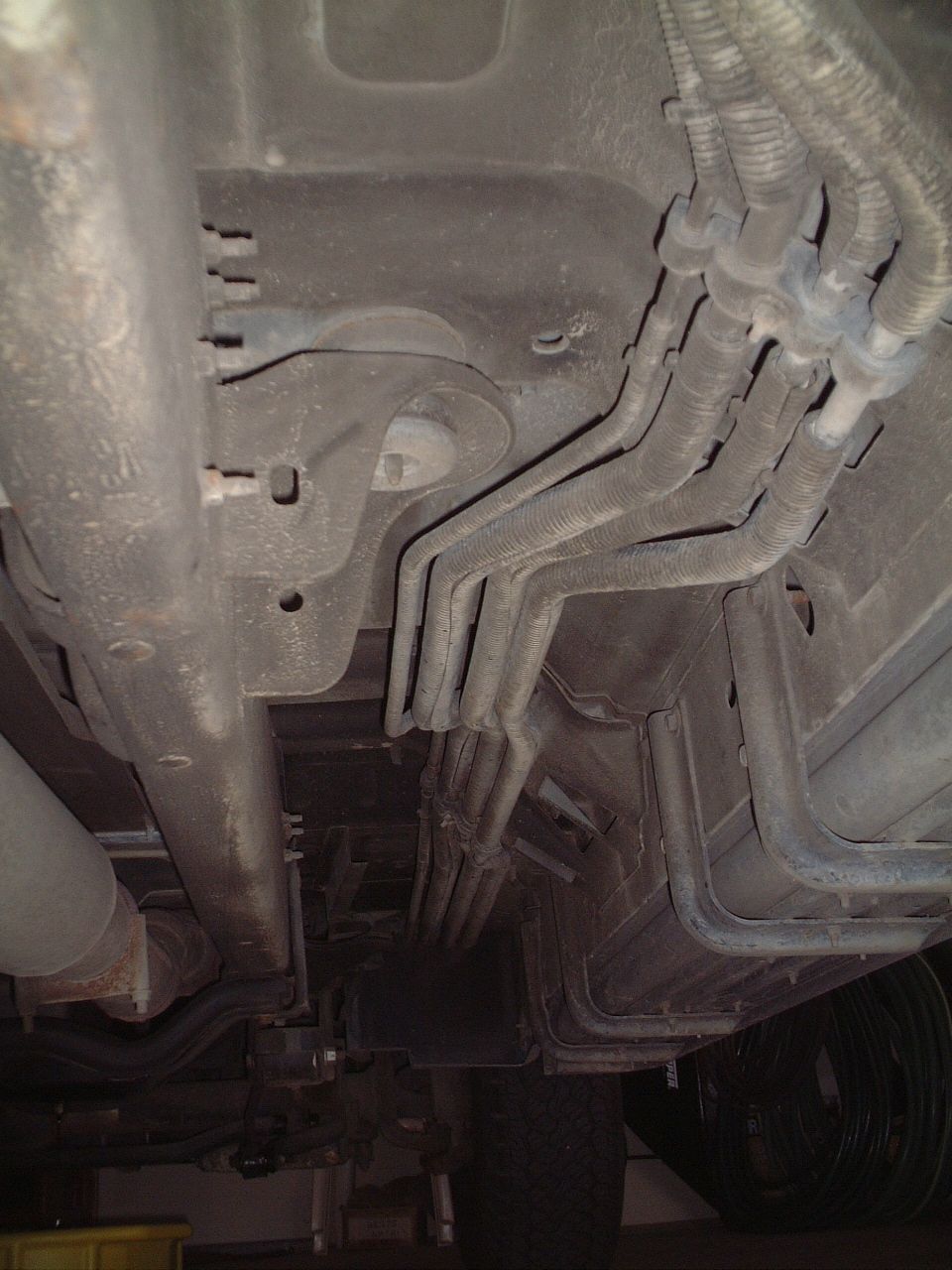 Underbody view of vehicle exhaust and brake lines along frame