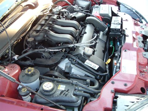 2001 Ford Taurus - The engine bay of a red 2001 Ford Taurus shows its V6 engine and associated components.