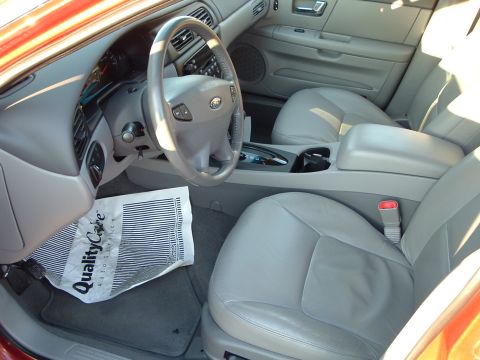 2001 Ford Taurus - The interior of a 2001 Ford Taurus shows light gray leather seats and a dashboard with a Ford emblem on the steering wheel.