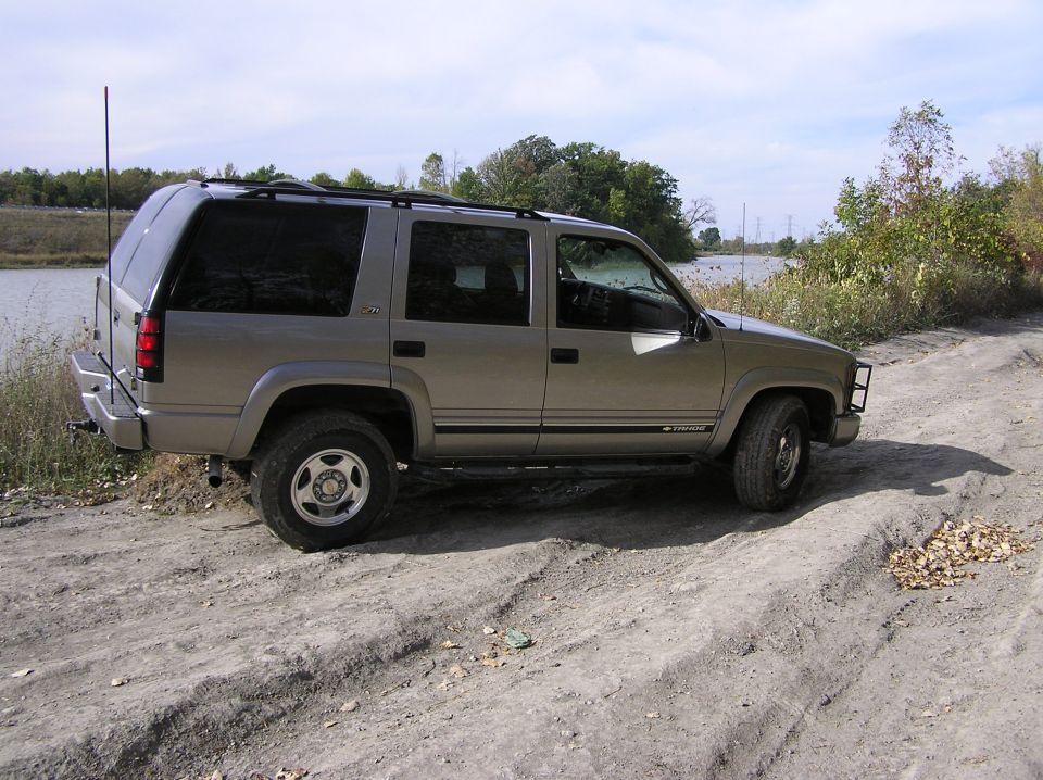 Tan SUV parked on a dirt road next to a body of water