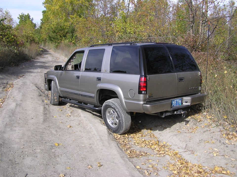 1999 Chevrolet Tahoe parked on a dirt road with trees in the background