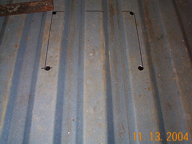 Corrugated metal bed floor with scribed rectangular access cutout and bolts, dated 2004.