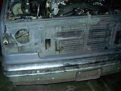 1987 Ford Bronco - The front of a vehicle shows its exposed engine components and radiator behind the grille.