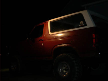 1986 Ford Bronco - Rear three-quarter view of a red 1986 Ford Bronco with a white removable top.