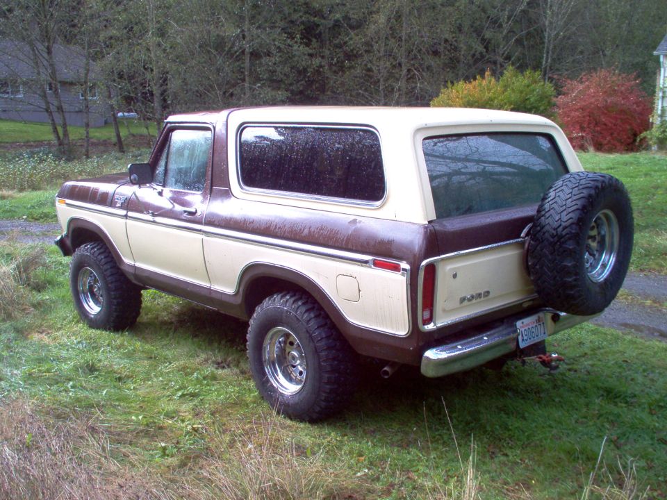 Rear 3/4 view of a two-tone brown and tan Ford Bronco SUV with rear spare tire on grass