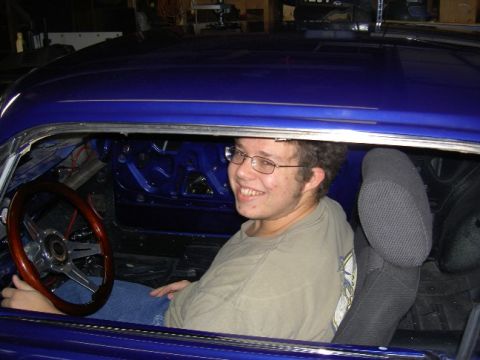 1965 Ford Mustang - A man sits inside the interior of a blue 1965 Ford Mustang, which appears to be undergoing restoration.