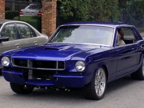 1965 Ford Mustang - A blue 1965 Ford Mustang coupe is parked next to another vehicle.