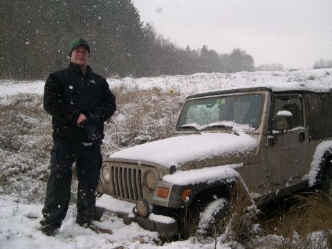 2003 Jeep TJ - A man stands beside a Jeep Wrangler partially buried in snow during a snowfall.