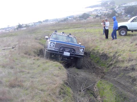 1998 Ford Ranger - A blue pickup truck navigates a muddy ditch while a white truck waits nearby.