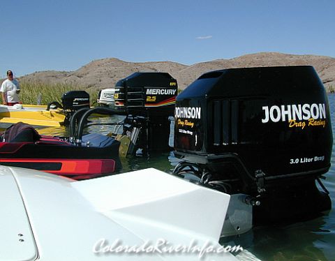 1991 Ford Bronco - Multiple boat motors are docked in the water under a clear blue sky with hills in the background.