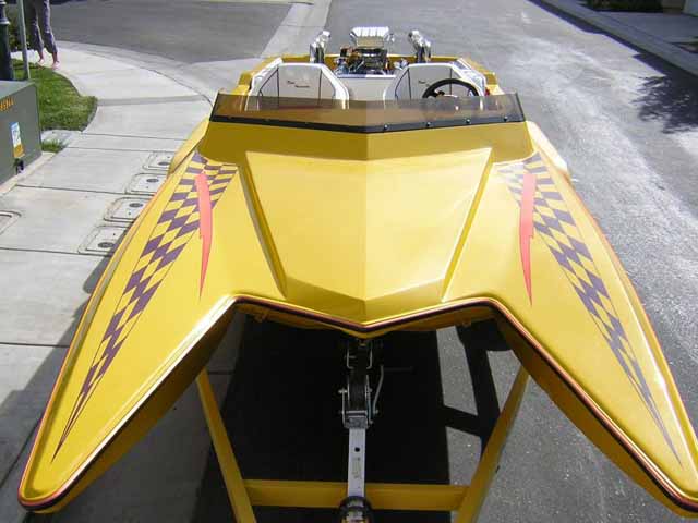 Yellow catamaran jet boat on trailer, checkerboard graphics and exposed chrome V8