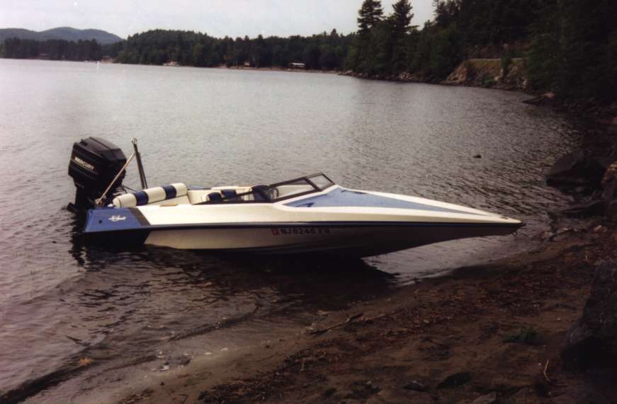 Speedboat pulled up on a rocky shore next to a lake