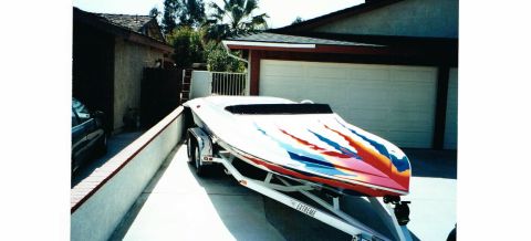 1991 Ford Bronco - A speed boat with a flame graphic design is parked on a trailer in a driveway.