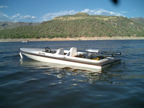 1991 Ford Bronco - A white boat with a brown trim floats on a lake with a desert landscape in the background.
