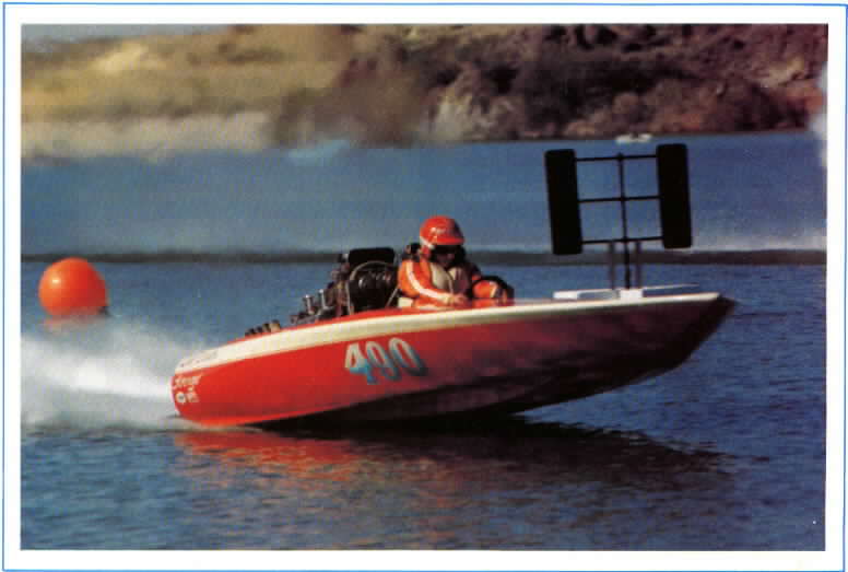 Red and white racing boat with number 400, driver in orange jacket and red helmet, on water