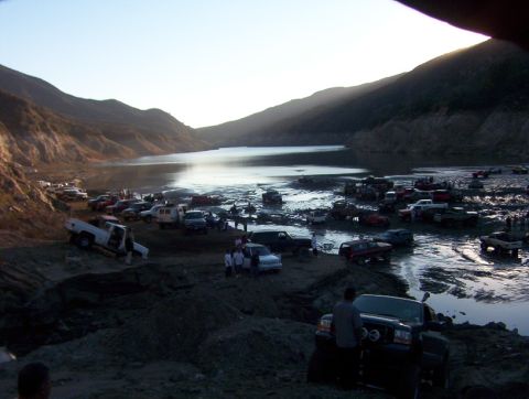 2000 Ford F-450 - A large gathering of trucks and SUVs are seen in a muddy, watery area with hills in the background.