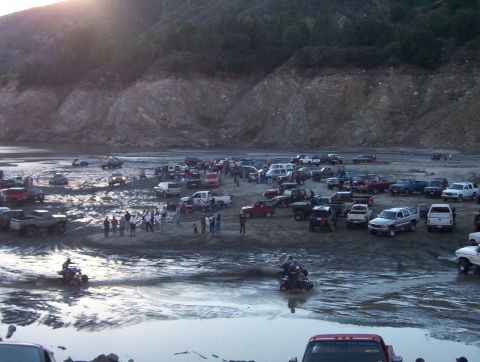 2000 Ford F-450 - A large gathering of trucks and SUVs are seen in a muddy, outdoor area with a hillside.
