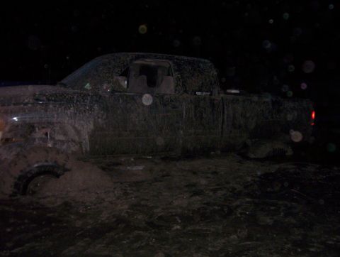 2000 Ford F-450 - A 2000 Ford F-450 is heavily covered in mud and stuck in dark, wet ground.
