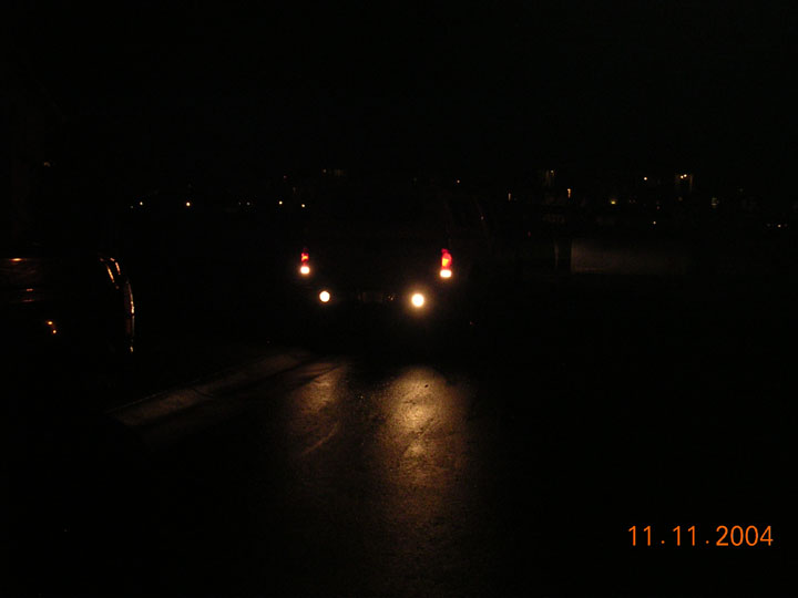 Pickup taillights and rear flood lights glowing on dark pavement at night
