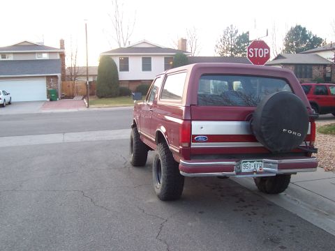 1991 Ford Bronco - Rear view of a maroon Ford Bronco parked on a street with houses in the background.