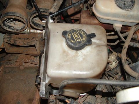 1990 Ford Bronco - Close-up of a vehicle's coolant reservoir and engine components.