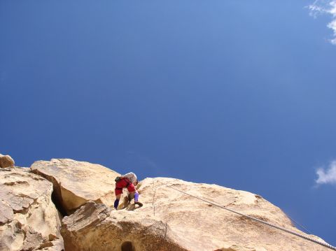1990 Ford Bronco - Climber scales a rock face with a rope, blue sky above. Supermotors.net logo visible.