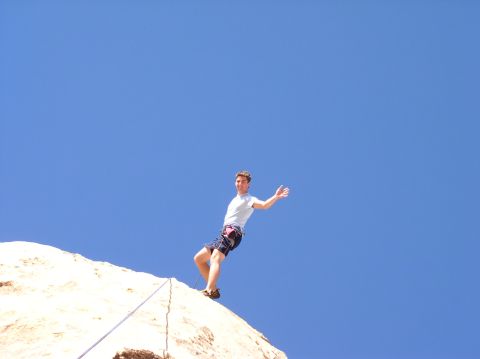 1990 Ford Bronco - A person rappels down a rock face under a clear blue sky, with a Supermotors.net watermark in the corner.