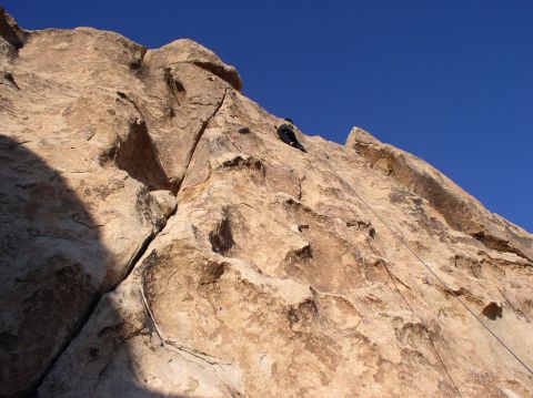 1990 Ford Bronco - A climber scales a steep rock formation on a sunny day.