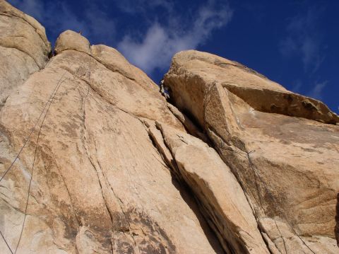 1990 Ford Bronco - Climbers scale a massive rock face, a challenging ascent against a bright blue sky.