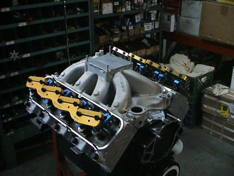 1979 Ford Bronco - A V8 engine is on a stand, an aftermarket intake manifold and performance components in a workshop setting.