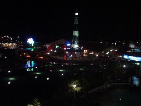 1996 Ford Probe - A nighttime scene of a lighthouse and illuminated buildings along a waterfront, with reflections visible in the dark water.