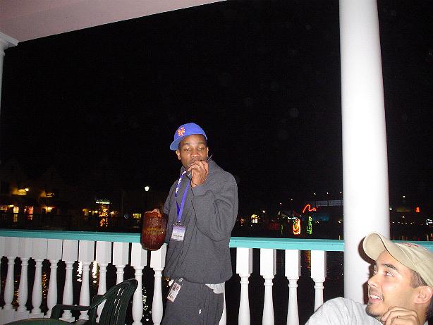 Two people on a balcony at night with lights in the background