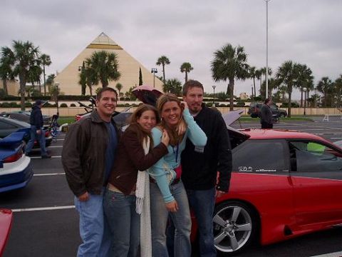 1996 Ford Probe - Two couples pose in front of a red coupe, with a pyramid-shaped building in the background.