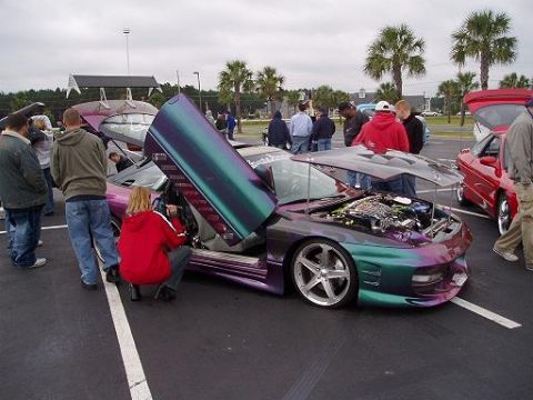 1996 Ford Probe - A customized 1996 Ford Probe is displayed with its butterfly doors and hood open, attracting attention from onlookers.