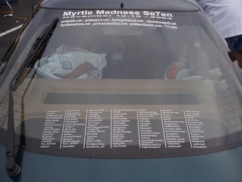 1996 Ford Probe - A car's rear window is covered in numerous stickers, some listing names and websites.