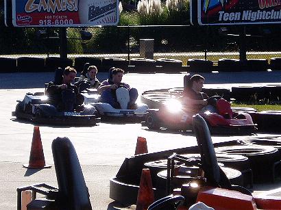 1996 Ford Probe - Go-karts race on a track under a bright sky, with advertising signs visible in the background.
