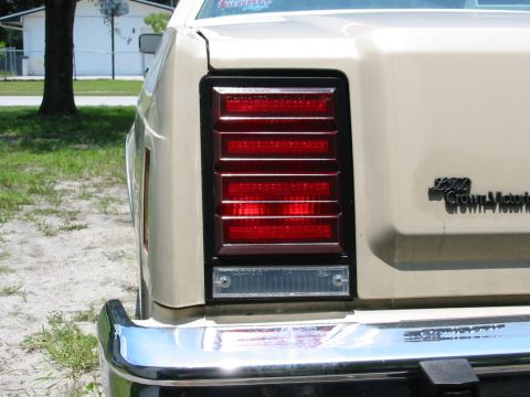 1985 Ford Crown Victoria LTD - Close-up of the rear taillight and 'Crown Victoria' badging on a tan sedan.