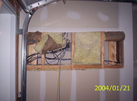 1986 Ford Bronco - A wall cavity is open, revealing insulation and electrical wiring, with a garage door track overhead.