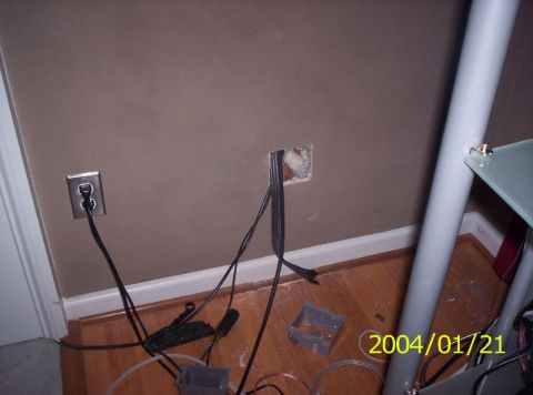 1986 Ford Bronco - A wall with an electrical outlet and an open junction box with wires is visible, along with a metal pole and part of a glass table.