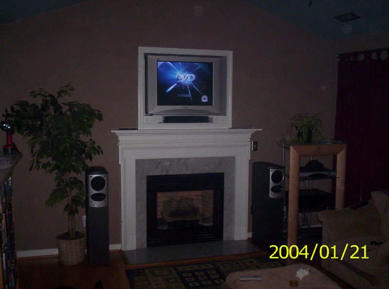Living room with fireplace, television, speakers, and a potted plant. Date stamp reads 2004/01/21