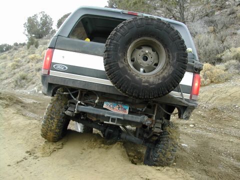1994 Ford Bronco - Ford Bronco rear view, stuck in dirt on a trail with spare tire mounted on back.