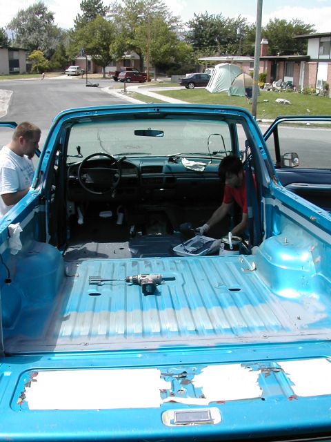 1994 Ford Bronco - The bed of a blue pickup truck is being prepped for a new coating, with tools and supplies visible.