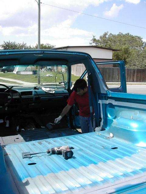1994 Ford Bronco - A person applies a coating to the interior and bed of a blue pickup truck.