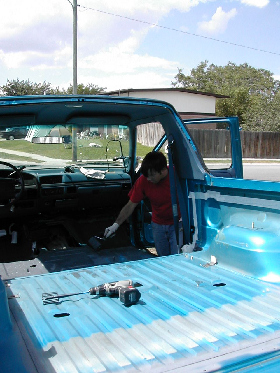 Blue pickup truck interior and bed with tools and paint